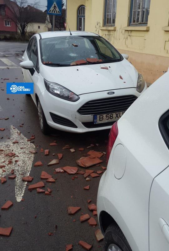 foto țigle smulse de pe un acoperiș de suflul unui avion. două mașini avariate