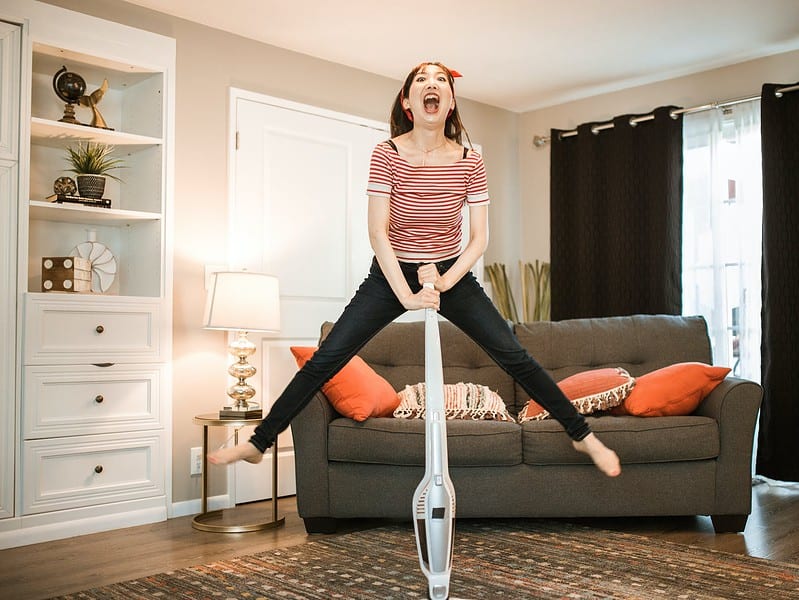a woman vacuuming while jumping