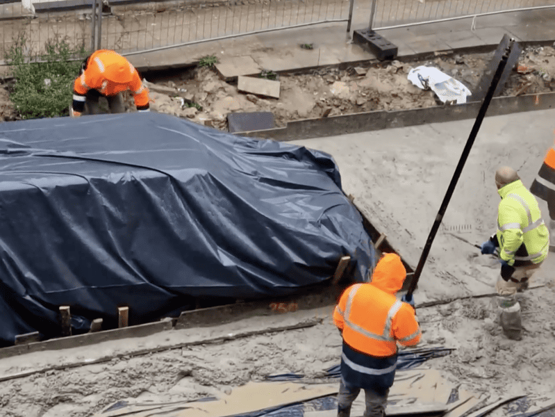 mașină ”îngropată” în asfalt. muncitorii au acoperit-o cu folie și au trurnat beton în jurul ei (video)