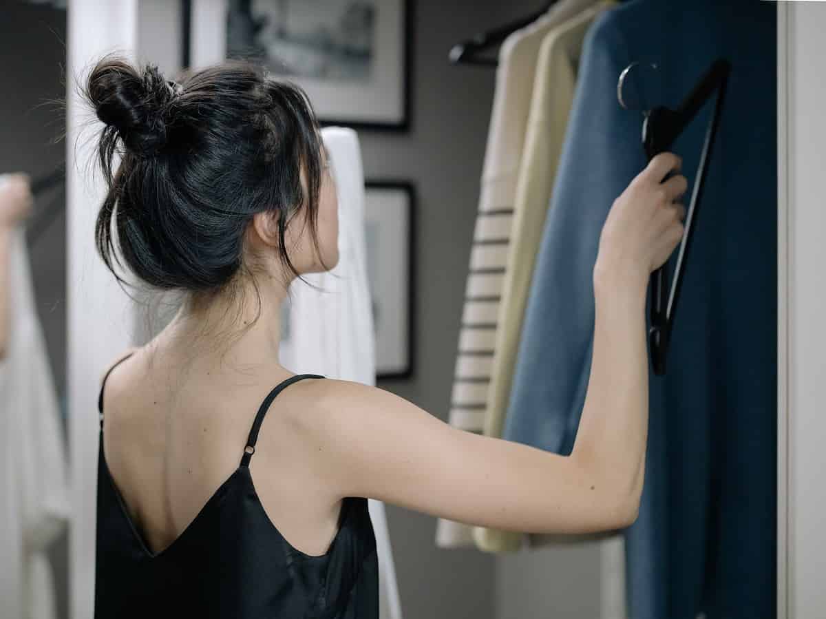 woman in black spaghetti nightdress putting a hanger inside a closet