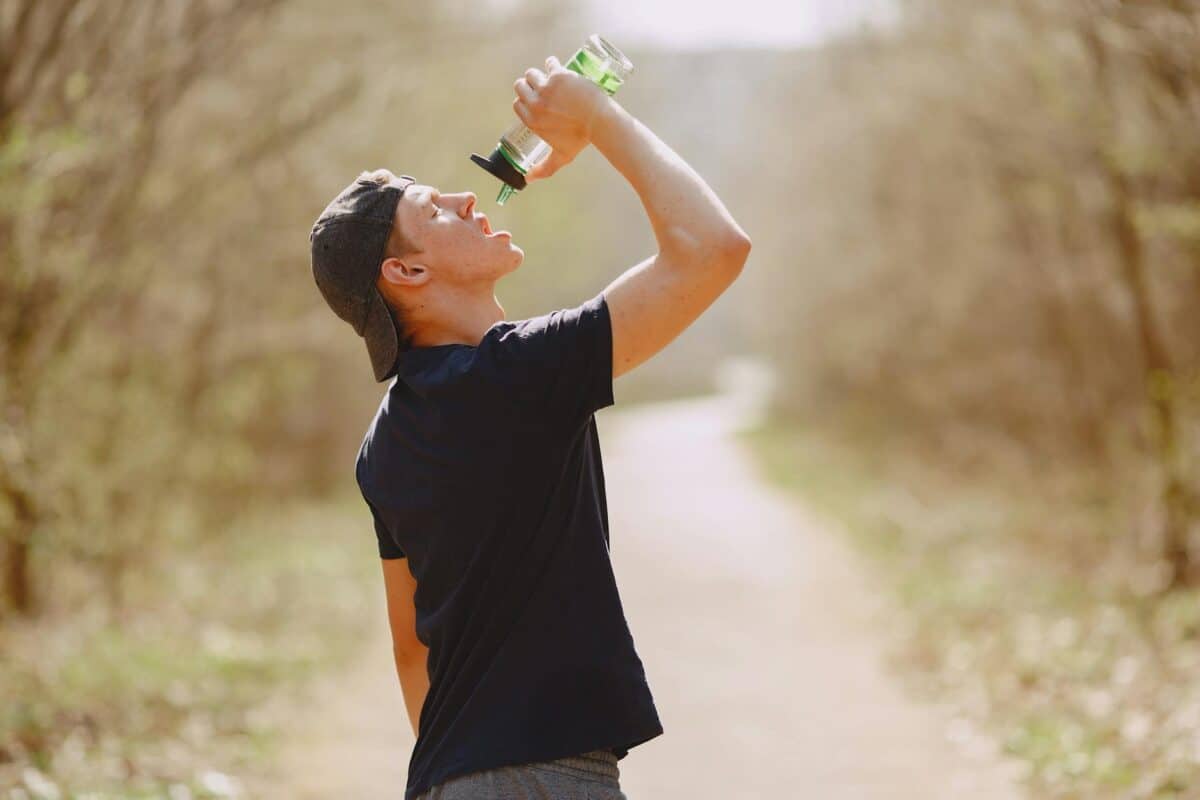 thirsty man drinking water during training in park